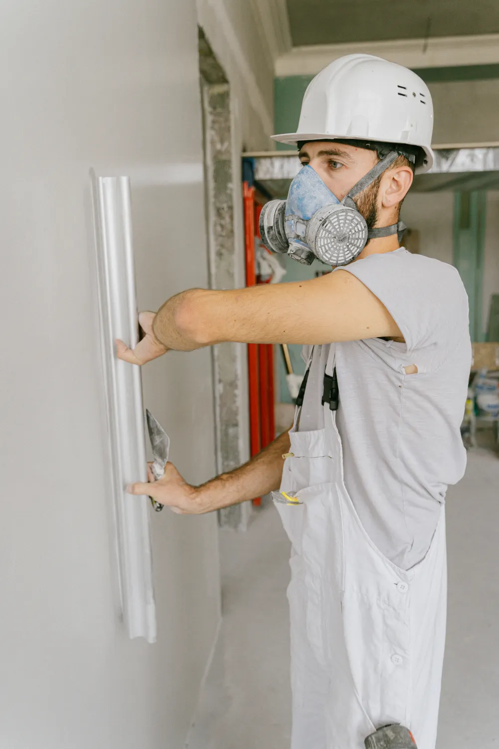 Construction worker checking a prepared wall surface with a straightedge and trowel