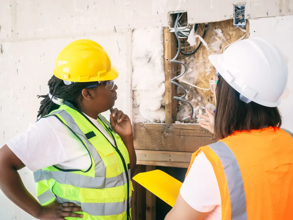 Two construction professionals inspecting exposed wall details on site