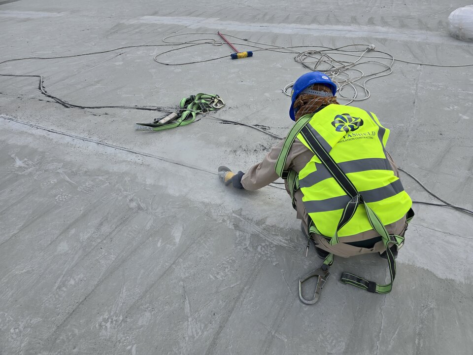 Worker carrying out waterproofing work on an exposed rooftop surface