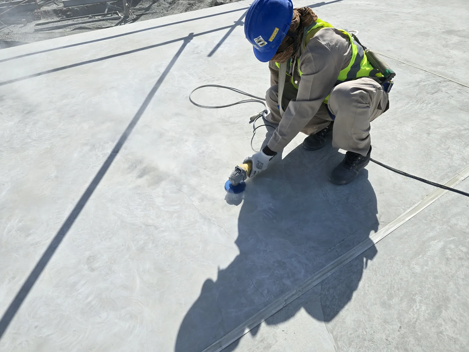 Worker preparing a rooftop surface with a handheld tool