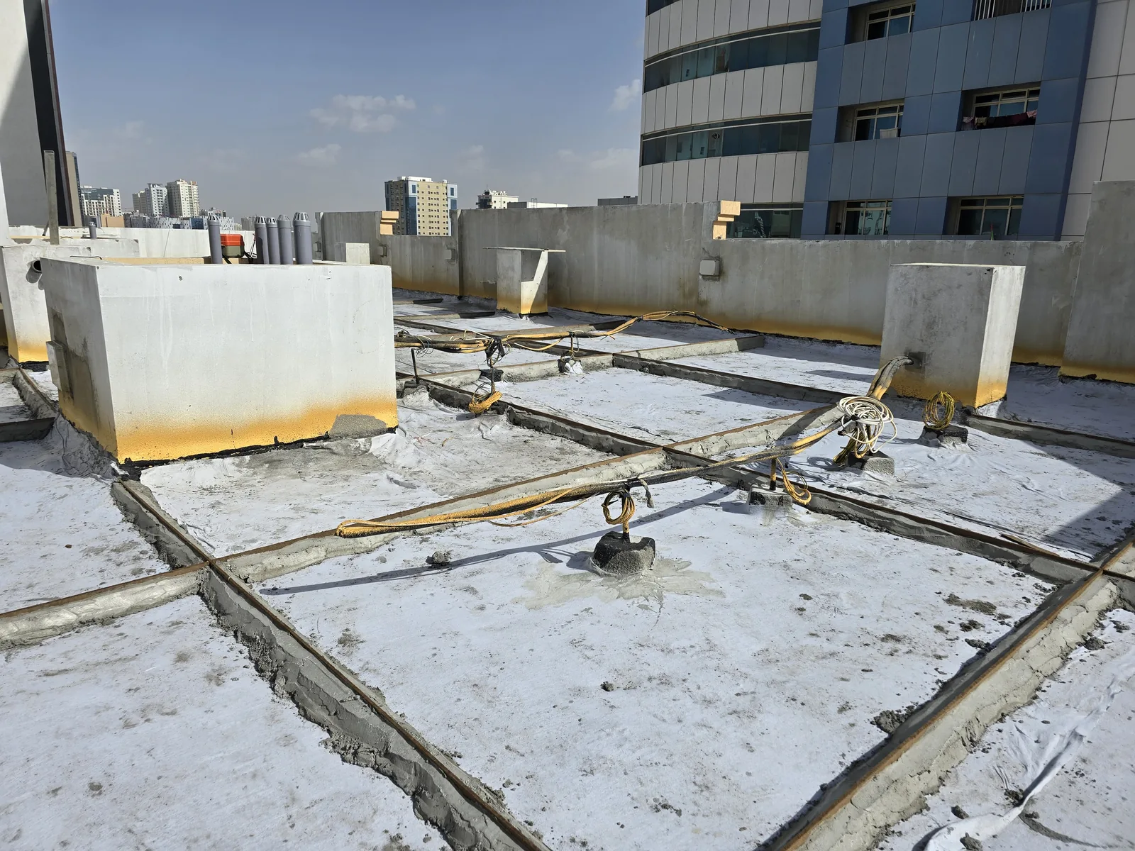 Waterproofing work across a rooftop with raised concrete service upstands