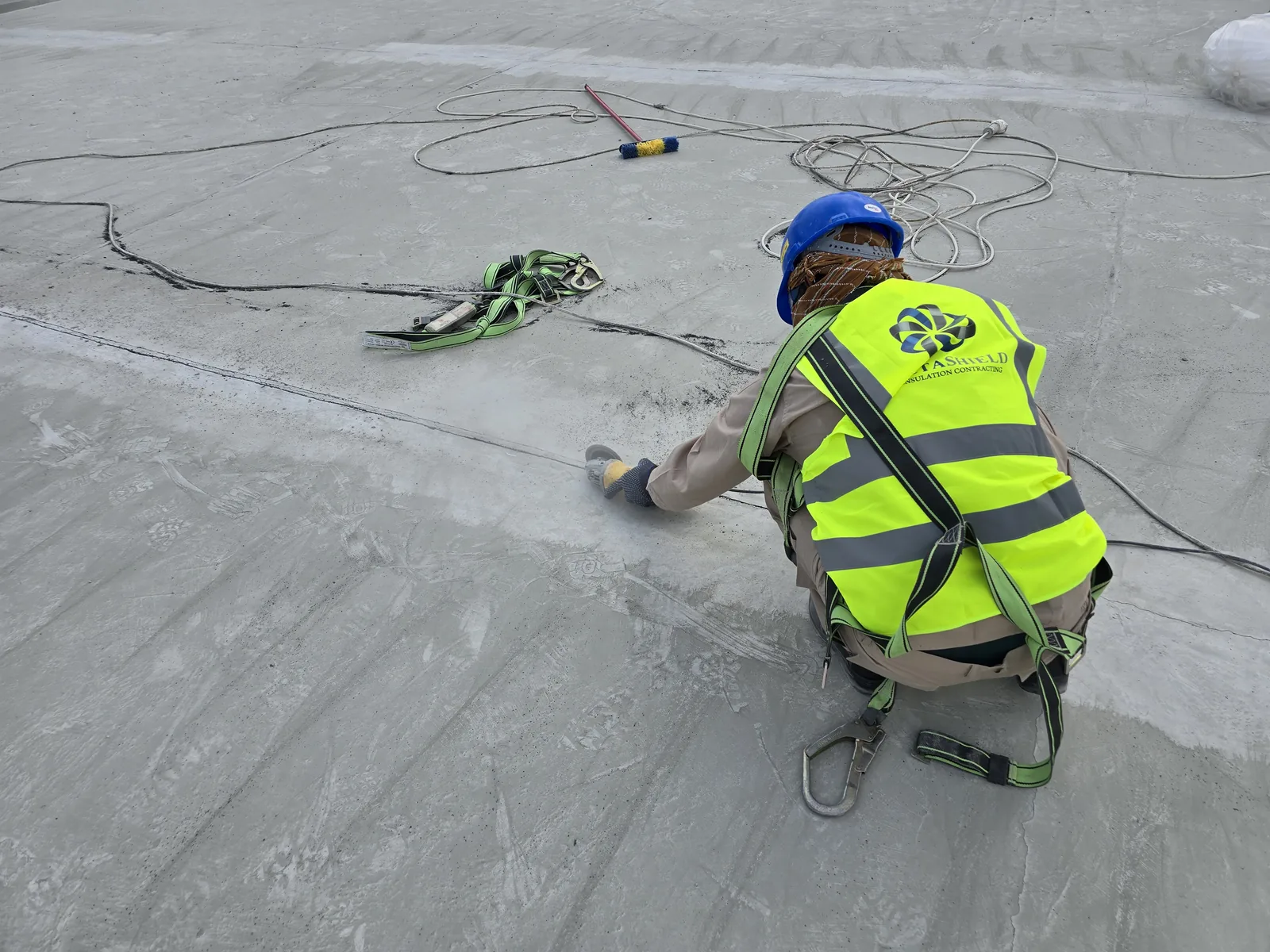 Worker carrying out waterproofing work on an exposed rooftop surface